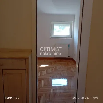 View from the hallway into an empty room with parquet flooring and a window. - image 12