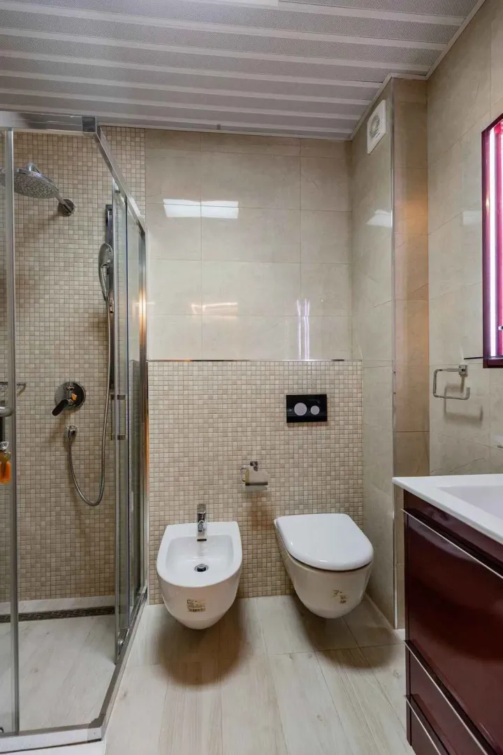 Moderne kupatilo sa tuš kabinom, umivaonikom i sanitarijama.