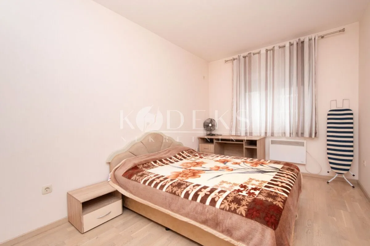 Bedroom with a double bed, nightstand, and a window with curtains.