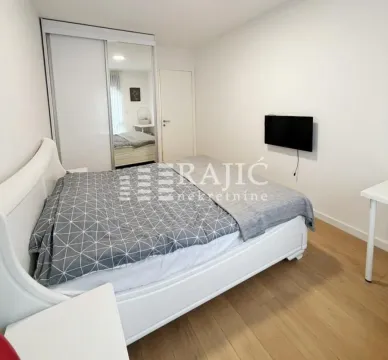 Furnished bedroom with a double bed, wardrobe, and TV. - image 9