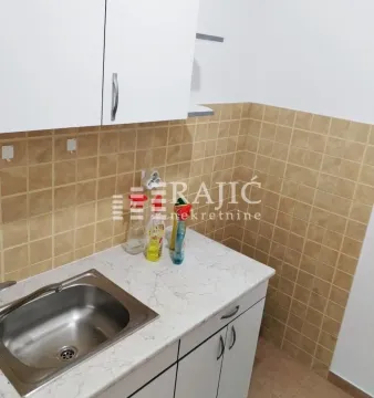 Smaller kitchen with a sink, white cabinets and ceramic tiles. - image 6