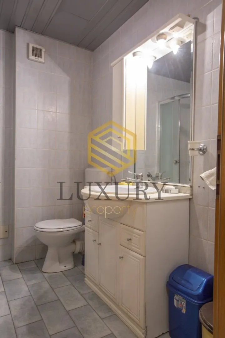Small bathroom with a vanity, cabinet, mirror, and toilet.