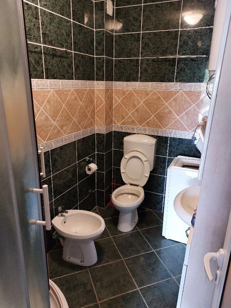 Kupatilo opremljeno sanitarijama, tuš kabinom i mašinom za veš.