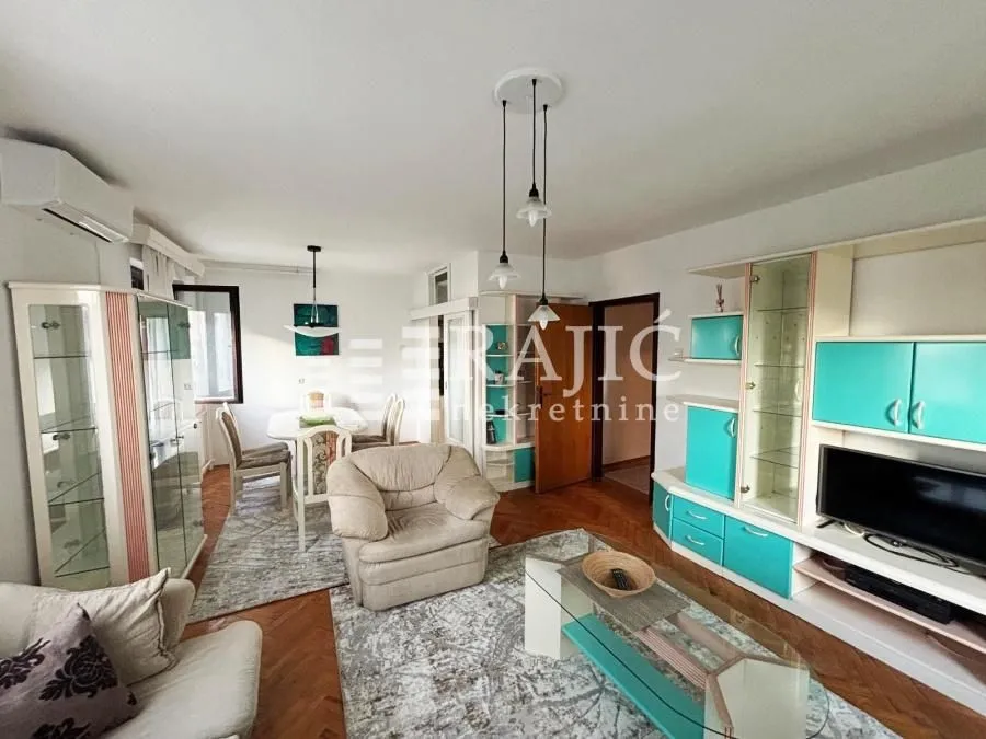 Spacious living room with seating area and dining space in the background.