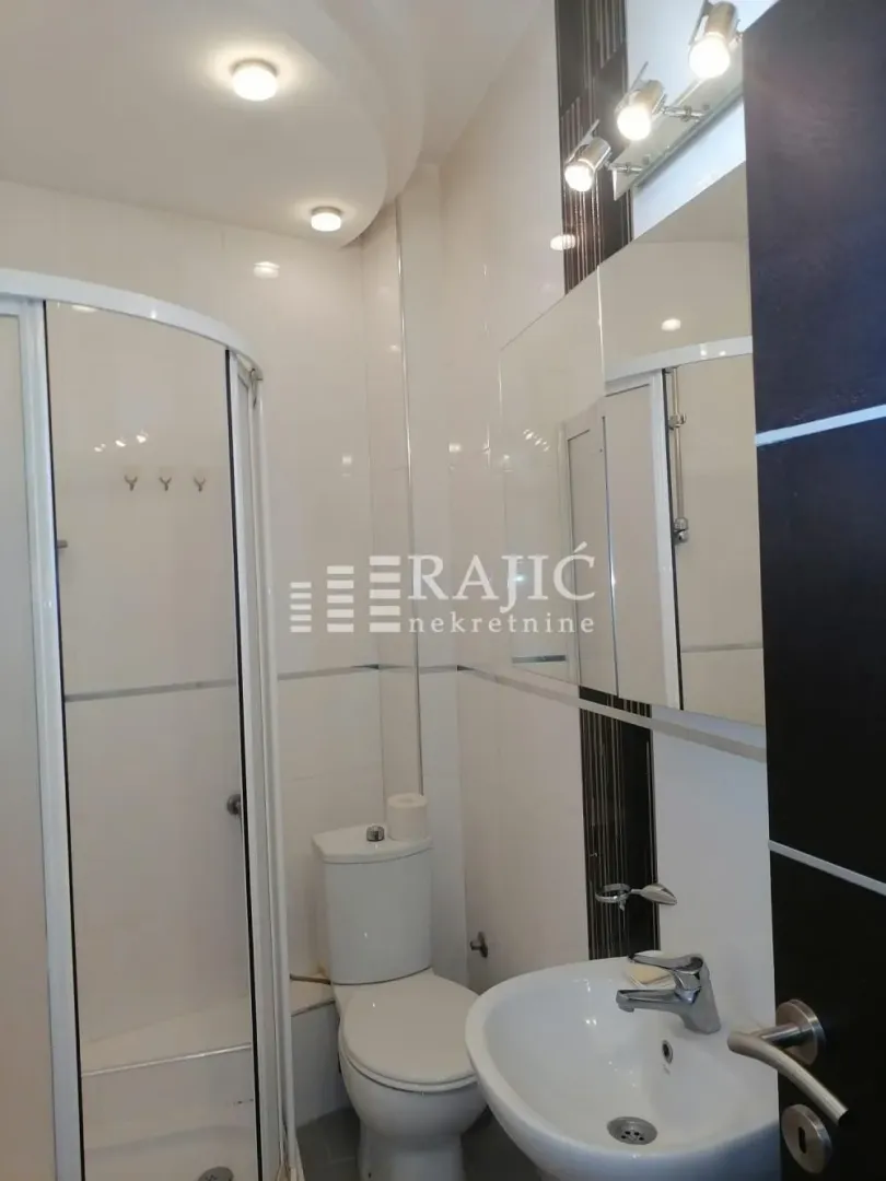 Modern equipped bathroom with a shower cabin, sink, and toilet.
