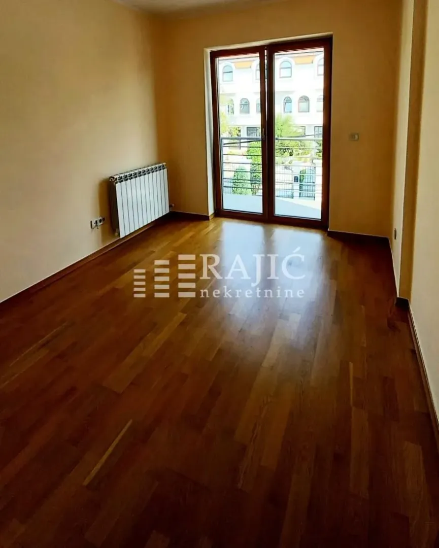 Empty room with hardwood floors and balcony doors.