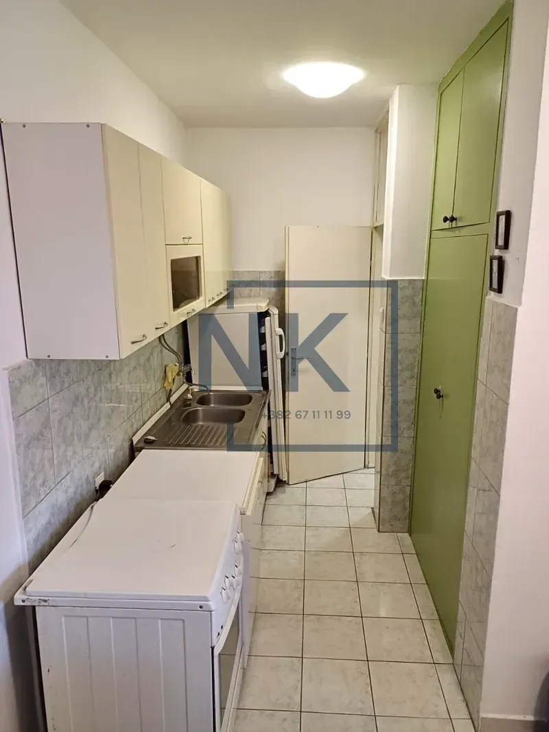 Small kitchen with white cabinets, a stove, and a built-in green closet.