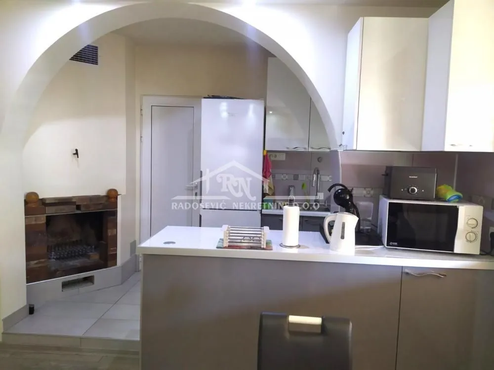 Kitchen with a breakfast bar and a fireplace in the background.