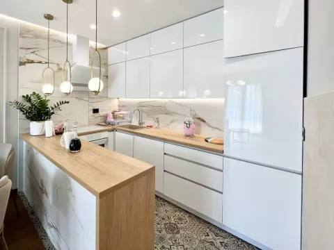 Modern kitchen with white cabinetry, wooden countertops, and a breakfast bar. - image 4