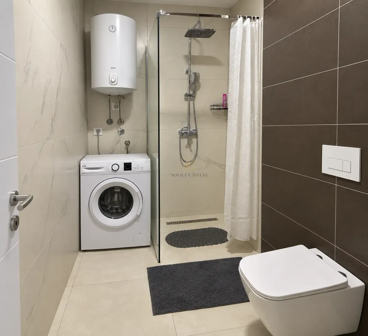 Kupatilo sa tuš kabinom, WC šoljom, veš mašinom i bojlerom.
