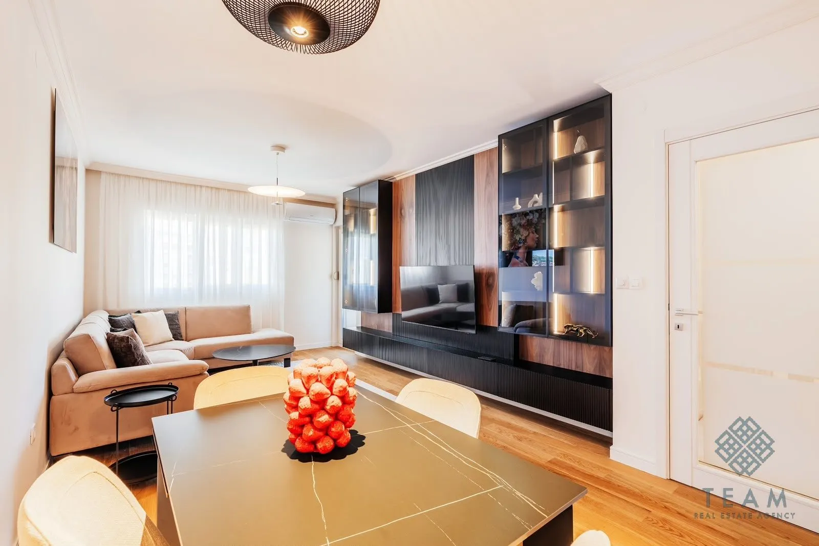 Living room with a dining area, sofa, and built-in wall units.