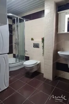 Bathroom equipped with a shower cabin, wall-hung toilet, and a sink with a mirror. - image 3
