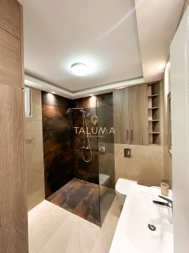 Modern bathroom with a walk-in shower, washbasin, toilet, and built-in cabinetry. - image 16