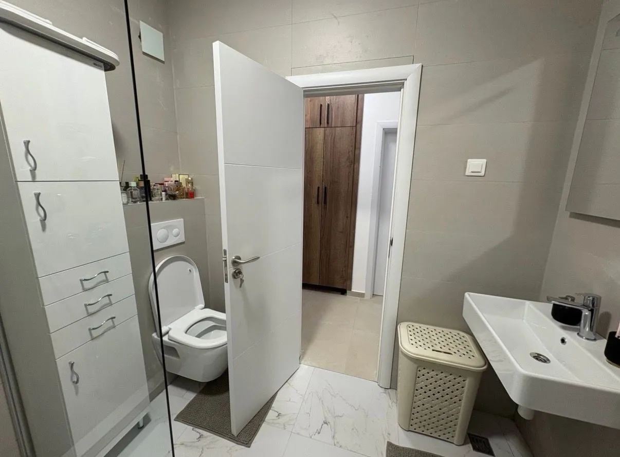 Savremeno opremljeno kupatilo sa sanitarijama i umivaonikom.