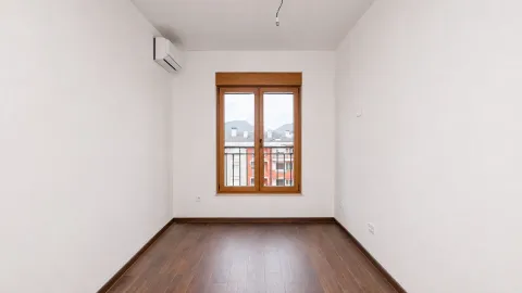 Empty room with wooden flooring, white walls, and a window. - image 8
