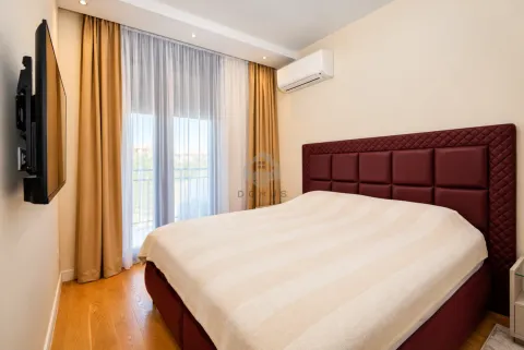 Spavaća soba sa velikim bračnim krevetom, televizorom na zidu i izlazom na terasu. - image 15