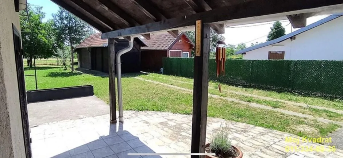 Pogled iz natkrivene verande na dvorište i okolne objekte.
