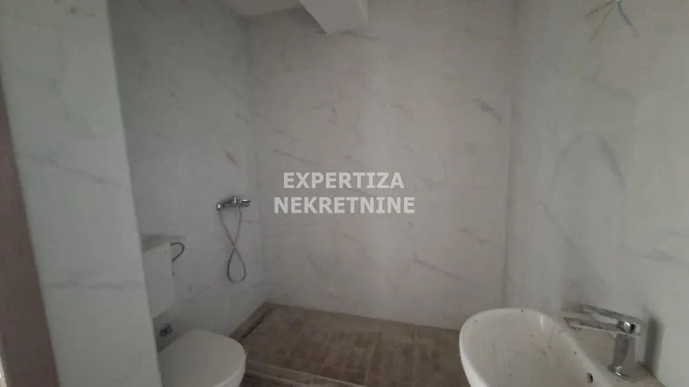Small furnished bathroom with white ceramic tiles and sanitary ware.