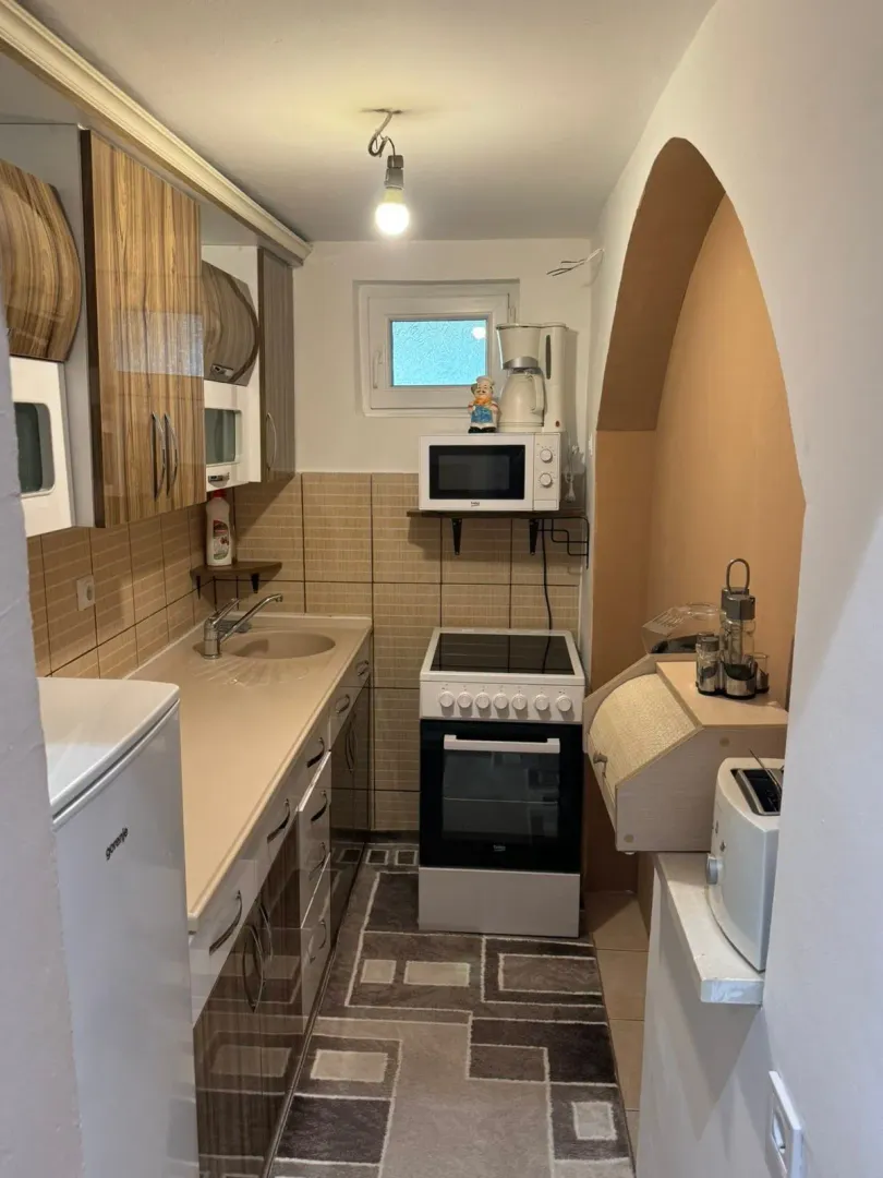 Small narrow kitchen with brown cabinets and a stove.