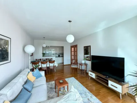 Spacious living room with a sofa, TV, and dining area in the background. - image 3