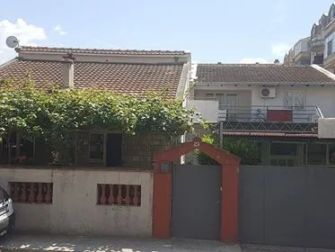 Vanjski izgled kuće sa dvorišnom kapijom i ogradom.