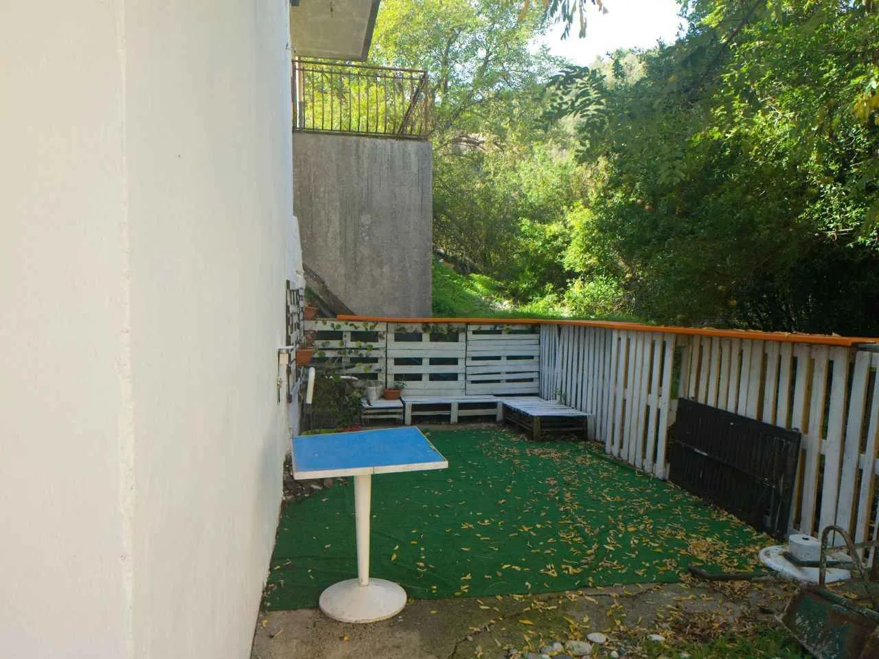 Dvorišna terasa sa vještačkom travom i garniturom od paleta.