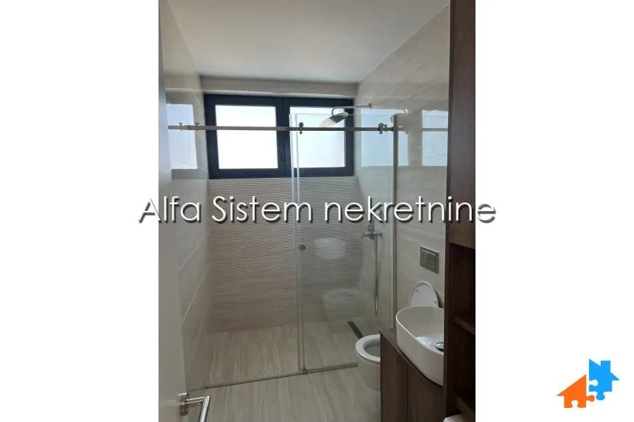 Modern bathroom with a walk-in shower, washbasin, and toilet.