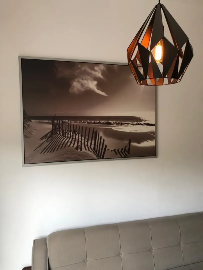 View of a living room section with a wall painting and a modern pendant light.