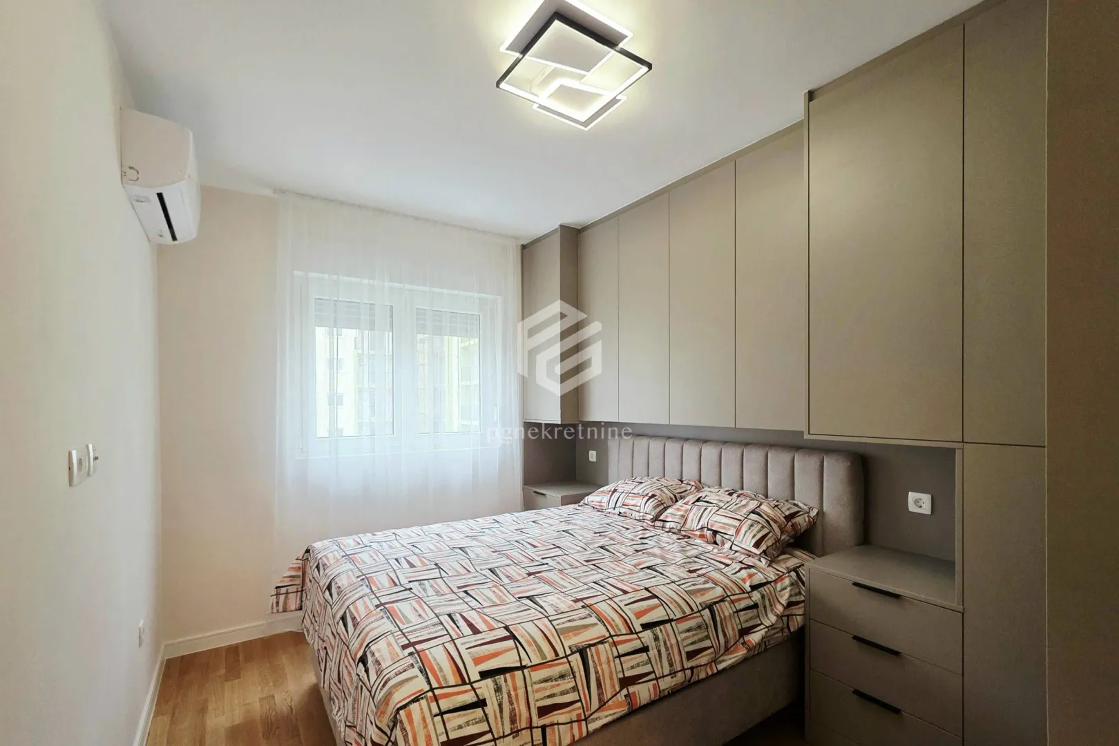 Furnished bedroom with a double bed, built-in wardrobes, and a window.