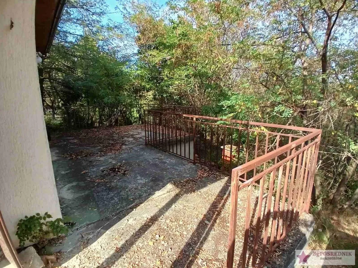 Terasa sa metalnom ogradom i pogledom na šumu.
