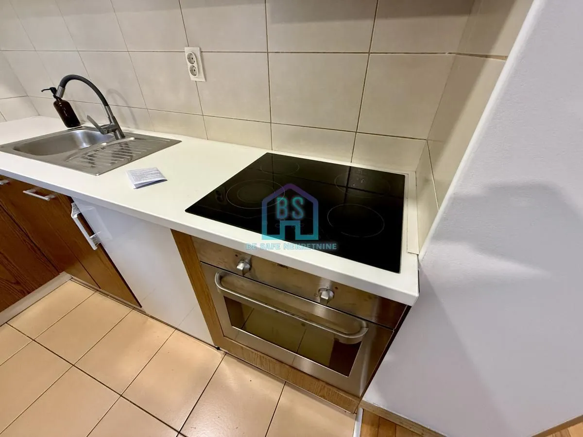 Deo kuhinje sa sudoperom, ugradnom rernom i keramičkom pločom.