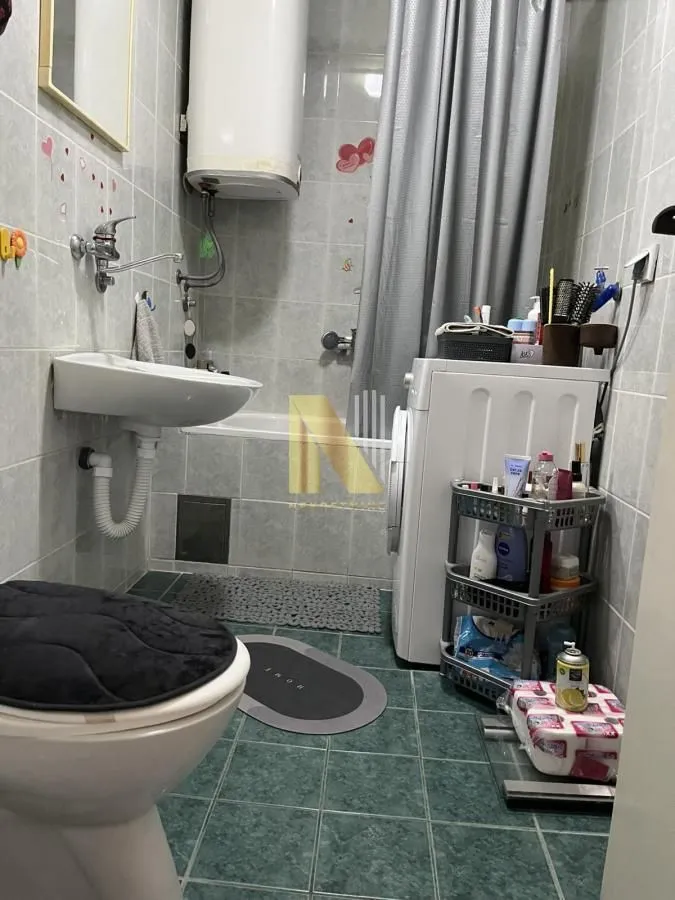 Manje kupatilo sa kadom, umivaonikom, veš mašinom i WC šoljom.