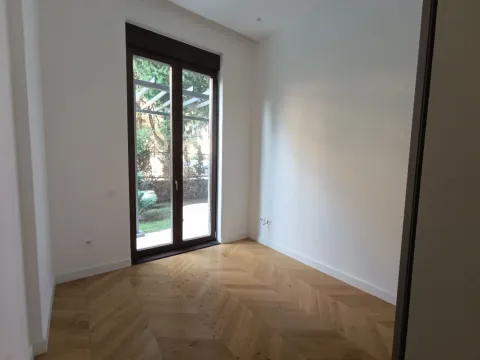 Prazna soba sa parketom i balkonskim vratima koja gledaju na dvorište. - image 13