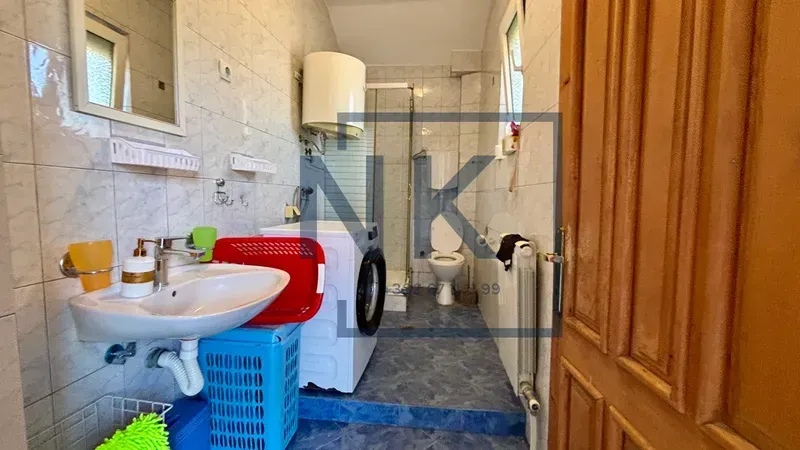 Manje kupatilo sa umivaonikom, veš mašinom, tuš kabinom i wc šoljom.