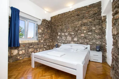 Spavaća soba sa bračnim krevetom i zidom od kamena. - image 5