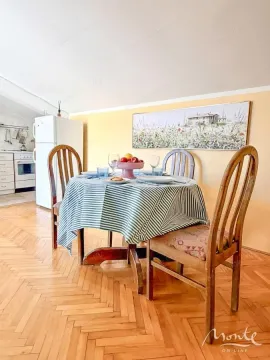 Trpezarija sa stolom, stolicama i pogledom na kuhinju u pozadini. - image 14