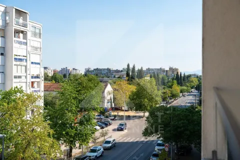 View from the terrace overlooking the city street, surrounding buildings, and greenery. - image 21