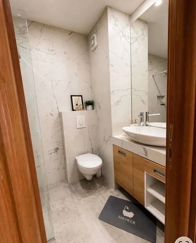 Modern bathroom with a washbasin, toilet, and walk-in shower.
