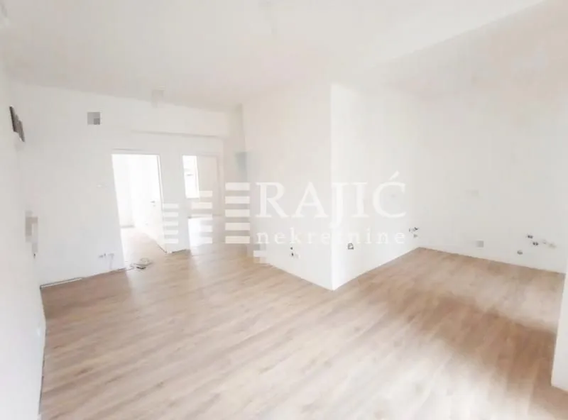 Empty room with light wooden flooring and white walls.