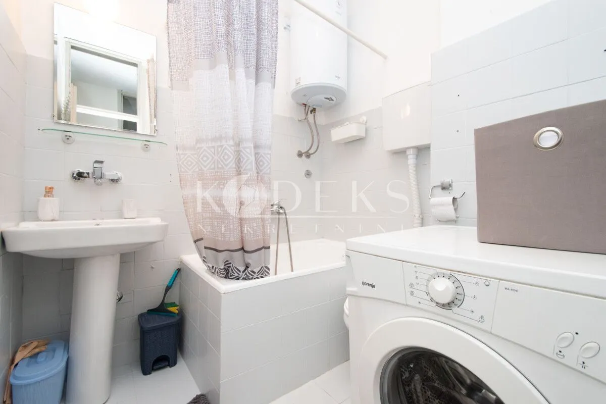 Bathroom equipped with a washbasin, bathtub, water heater, and washing machine.