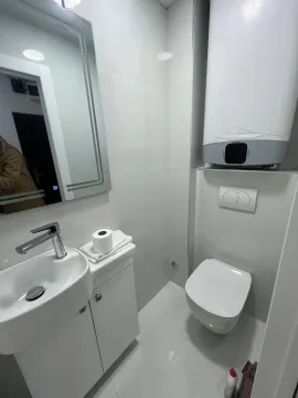 A modern and functional bathroom featuring white tiles, a sink, and a toilet. - image 16