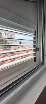 View through a window with blinds overlooking the neighborhood and roofs. - image 6