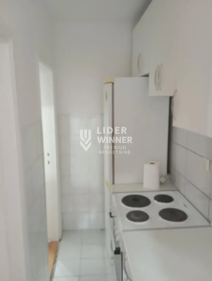 Manja bela kuhinja sa štednjakom i frižiderom.