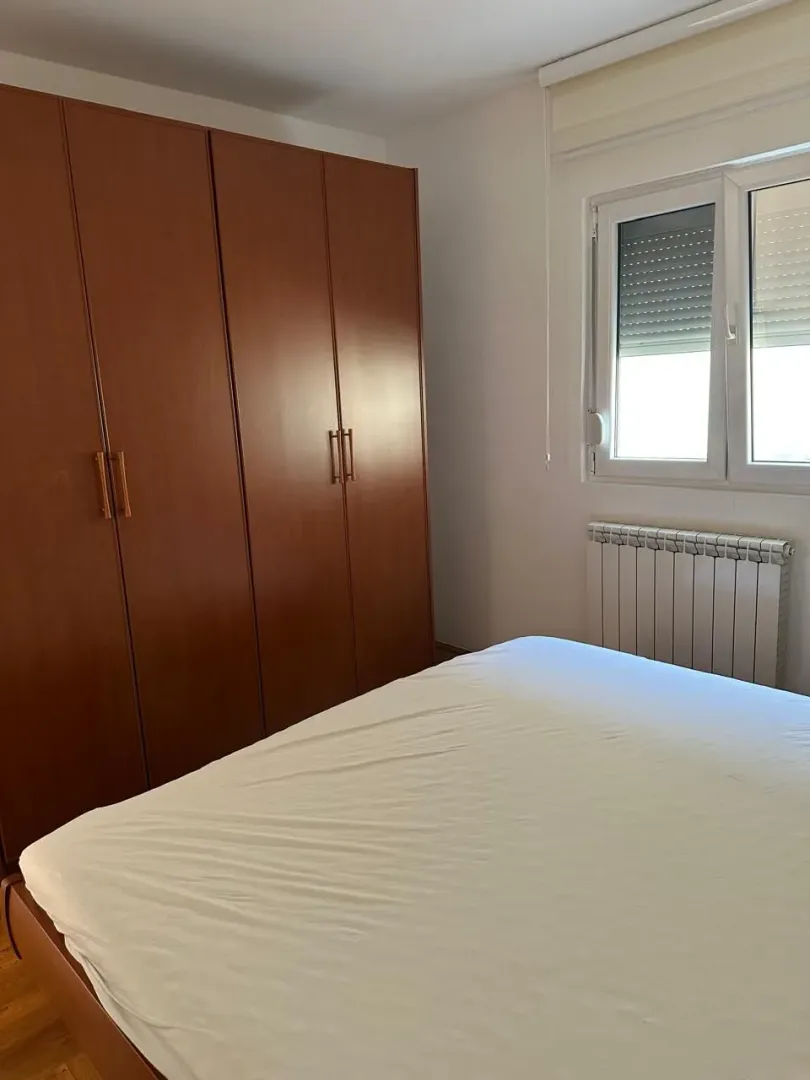 Bedroom with a double bed, wooden wardrobe, and window.