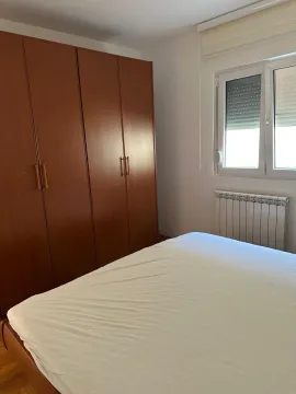 Bedroom with a double bed, wooden wardrobe, and window. - image 14