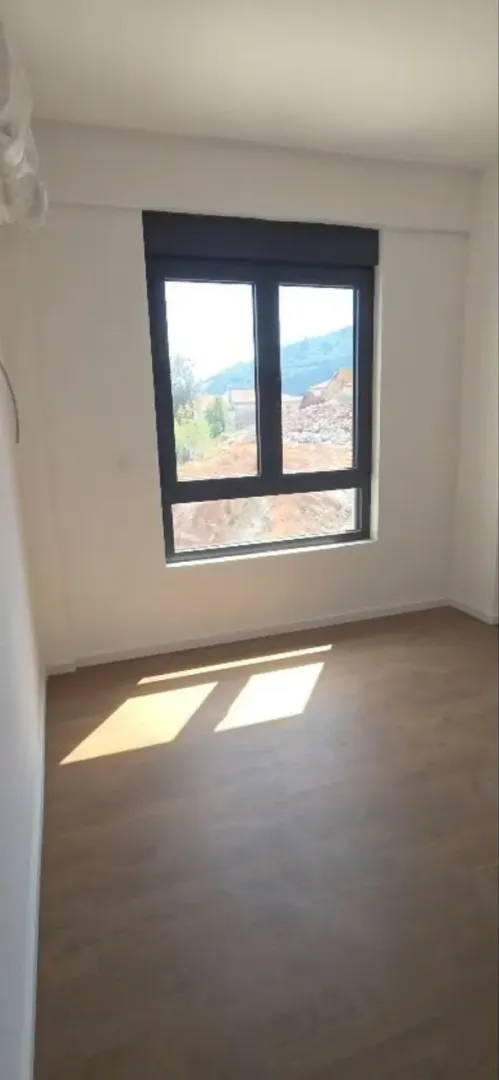 Prazna soba sa prozorom i pogledom na prirodu.