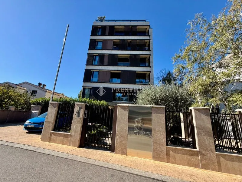 Exterior view of a modern residential building with a fence and yard.