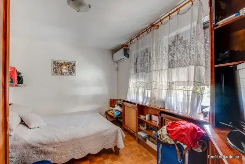 Small bedroom with a bed, a window with white curtains, and wooden shelving units. - image 13