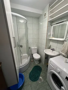 A bathroom with a shower cabin, sink, and washing machine. - image 8