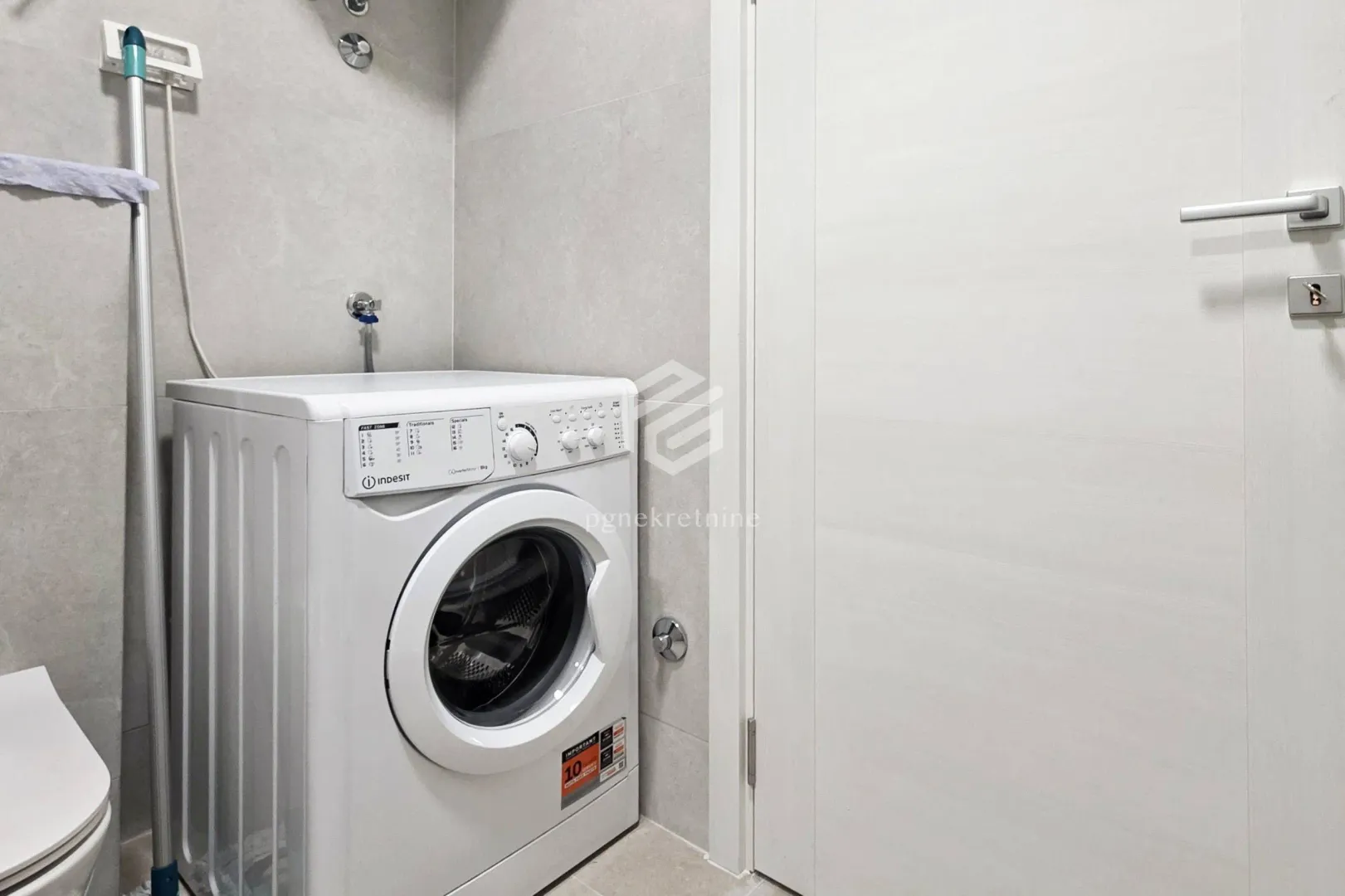 Bathroom with a washing machine and white door.